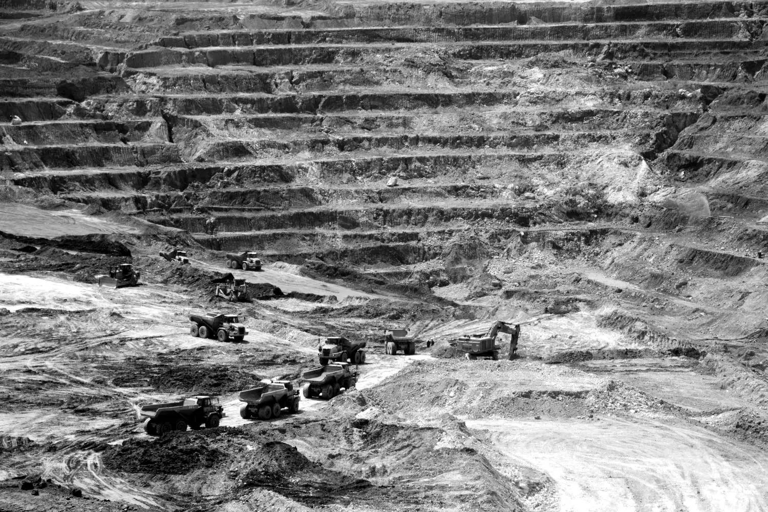 Open pit mine with haul trucks, dozers and a Hitachi excavator at work on the pit floor