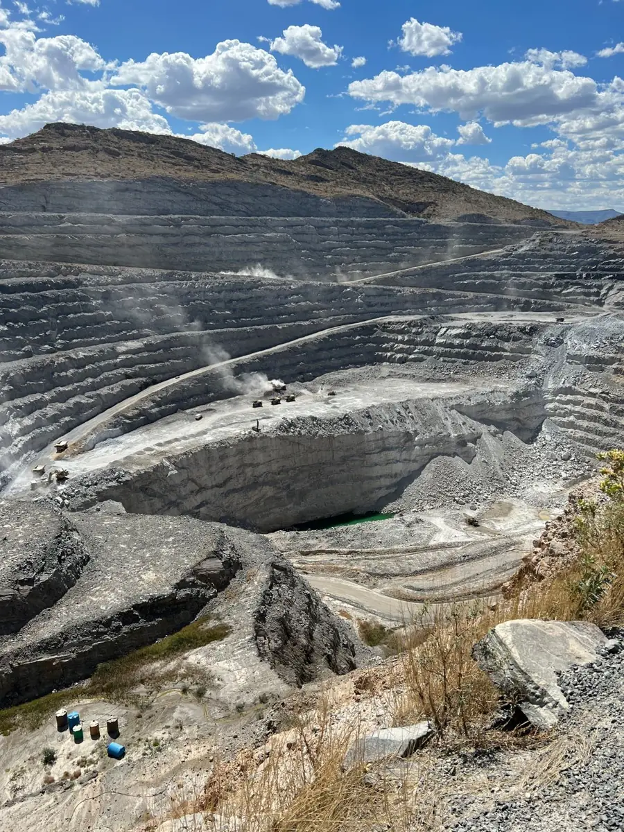 Deep open pit mine with haul roads and trucks, seen from the rim